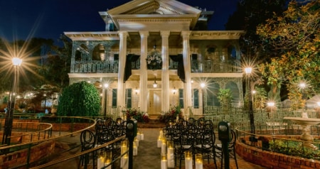 The Haunted Mansion with columns and ornate balconies illuminated for an evening wedding ceremony with candles