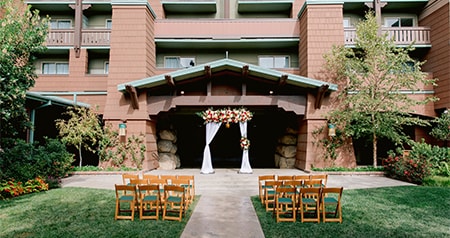 An outdoor wedding ceremony venue with chairs in a garden along an aisle leading to an archway at Disney’s Grand Californian Hotel and Spa