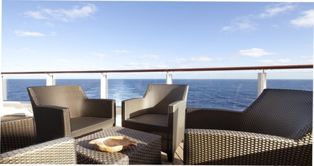 An outdoor patio with chairs and a table overlooks the ocean