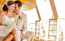 A smiling bride and groom sit together on a ship's patio