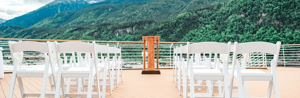 Folding chairs on the deck of ship overlooking a hillside