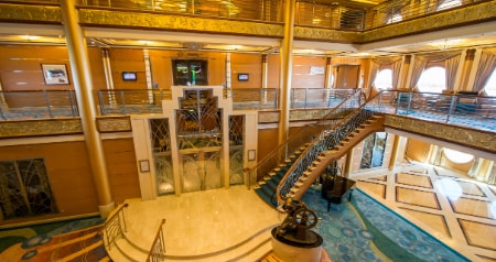 The Atrium in the Disney Dream featuring a staircase, grand piano and statue of Helmsman Mickey Mouse