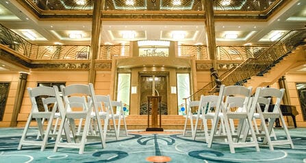 A few rows of chairs facing a wooden podium inside The Atrium