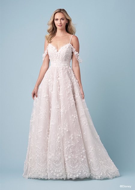 A bride wearing a Snow White inspired A line wedding gown featuring a V neckline, embroidery, spaghetti straps and lace off the shoulder sleeves
