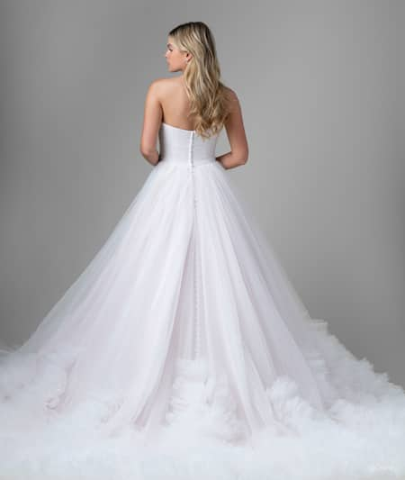 The back of a bride wearing a Rapunzel inspired ball gown featuring a train with ruffles around the hem