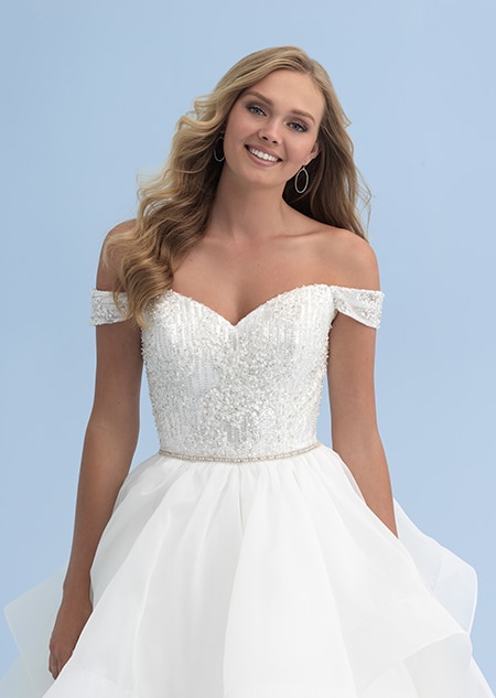 A close up of a woman in an off the shoulder wedding dress with a beaded bodice