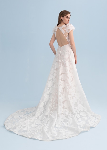 A woman looking over her shoulder wearing a lacy wedding dress with an open back A woman looking over her shoulder wearing a lacy wedding dress with an open back