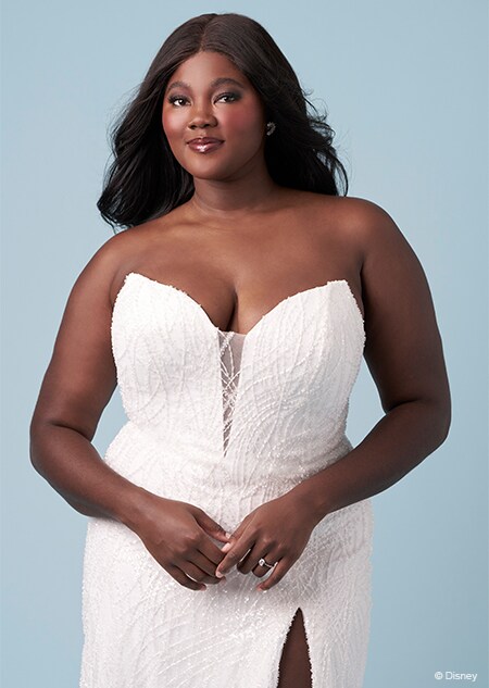 A bride wearing a strapless Ariel inspired sheath gown featuring an illusion neckline and a high slit