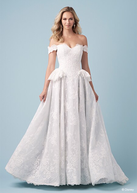 A bride wearing a Cinderella inspired A line gown featuring off the shoulder sleeves, a sweetheart neckline and short panniers on the hips
