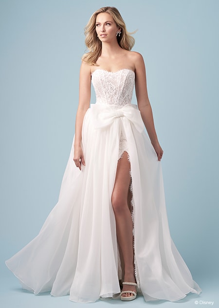 A bride wearing a strapless Snow White inspired sheath dress featuring an embroidered bodice and a high slit