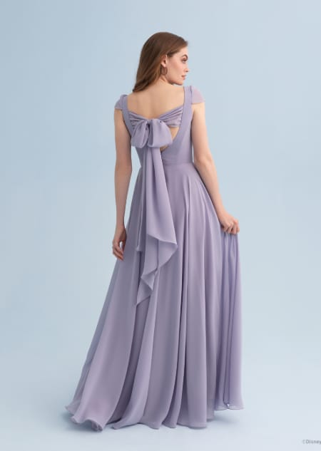 A woman wearing a Rapunzel themed bridesmaid dress with a bow across the back