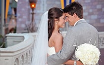 A bride and groom cuddle in front of Cinderella Castle