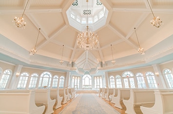 The interior of Disney's Wedding Pavilion reveals a rotunda with pews and a chandelier