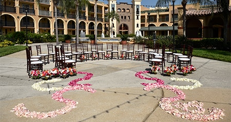 Rose petals lead to a group of chairs arranged in a semi circle on a courtyard with a large water fountain