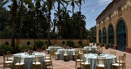 Five circular tables with chairs arranged in the La Mesa Patio courtyard surrounded by plants