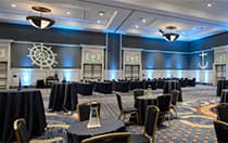 A large light fixture hangs from the ceiling over several small circular tables