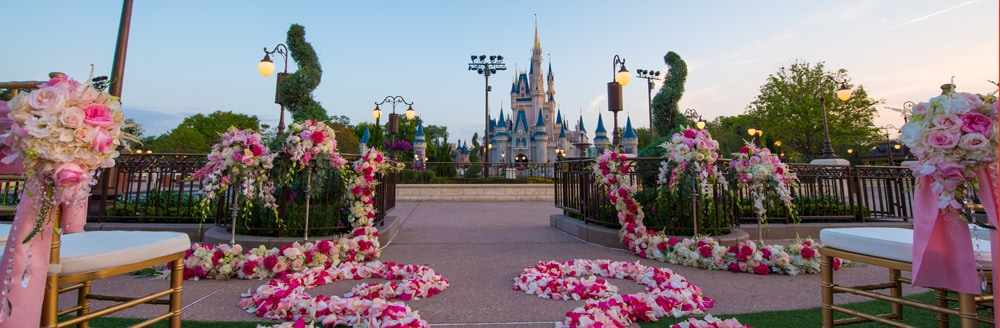Cinderella's Castle stands in the background of an outdoor wedding venue set with chairs and floral arrangements