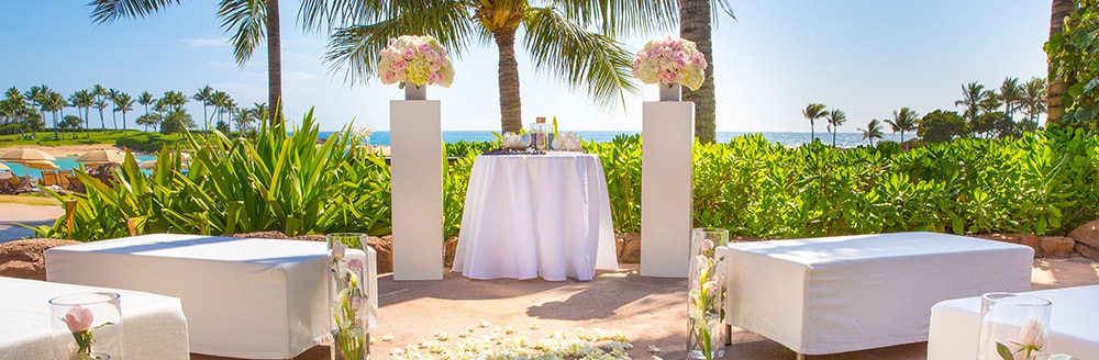 Large benches pointed towards an altar decorated with bouquets of flowers at a beach