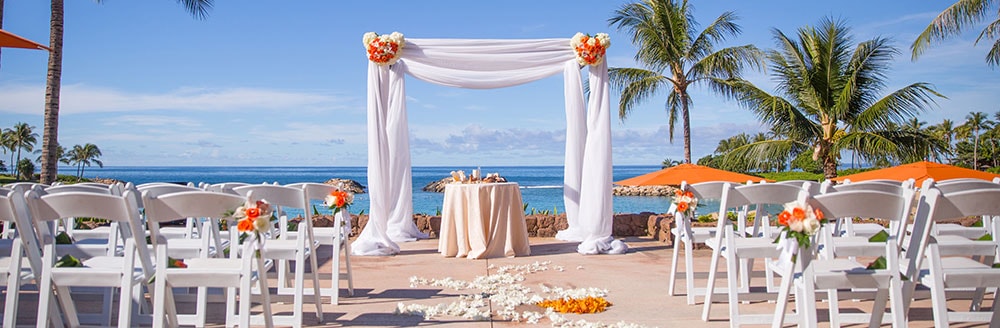 A wedding altar and chairs scattered with flower petals for a ceremony by the sea