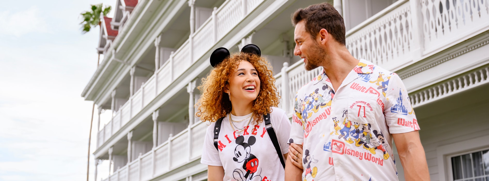 A couple wearing Disney shirts standing in front of Disney's Grand Floridian Resort & Spa