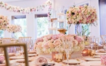 A table setting with crystal glassware, wedding dinnerware, candles and a centerpiece of roses