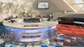 Test A room with modern décor, and check–in desk with a sign reading "Disney Vacation Club Member Lounge"