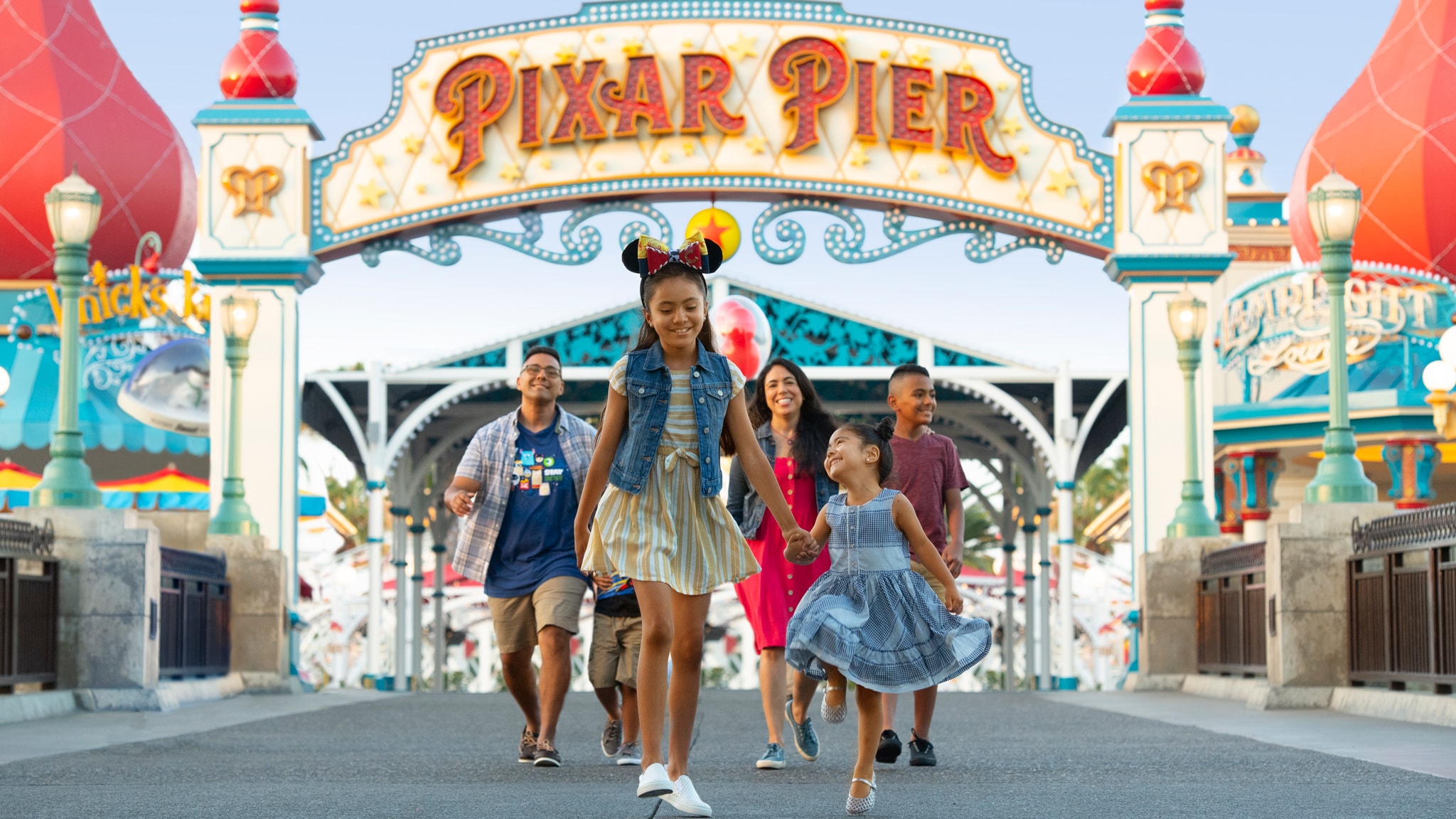 A family of six strolls under the Pixar Pier archway at Disney California Adventure Park