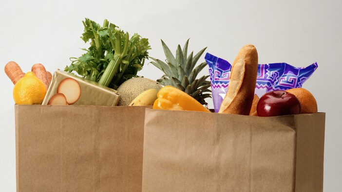 リンゴ、セロリ、バゲットなどの食べ物が見える食料品の袋 2 つ