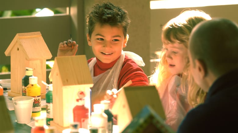 A man helps a boy and girl make crafts
