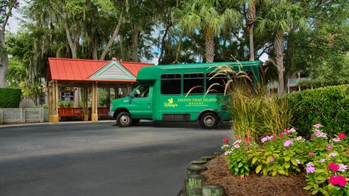 The Disney's Hilton Head Island Resort shuttle parked under palm trees outside the entrance