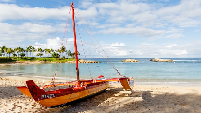 A small sailboat on a sandy beach by the ocean