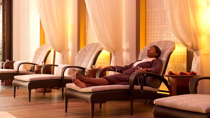 A woman dressed in a robe, sitting on a lounge chair in the spa