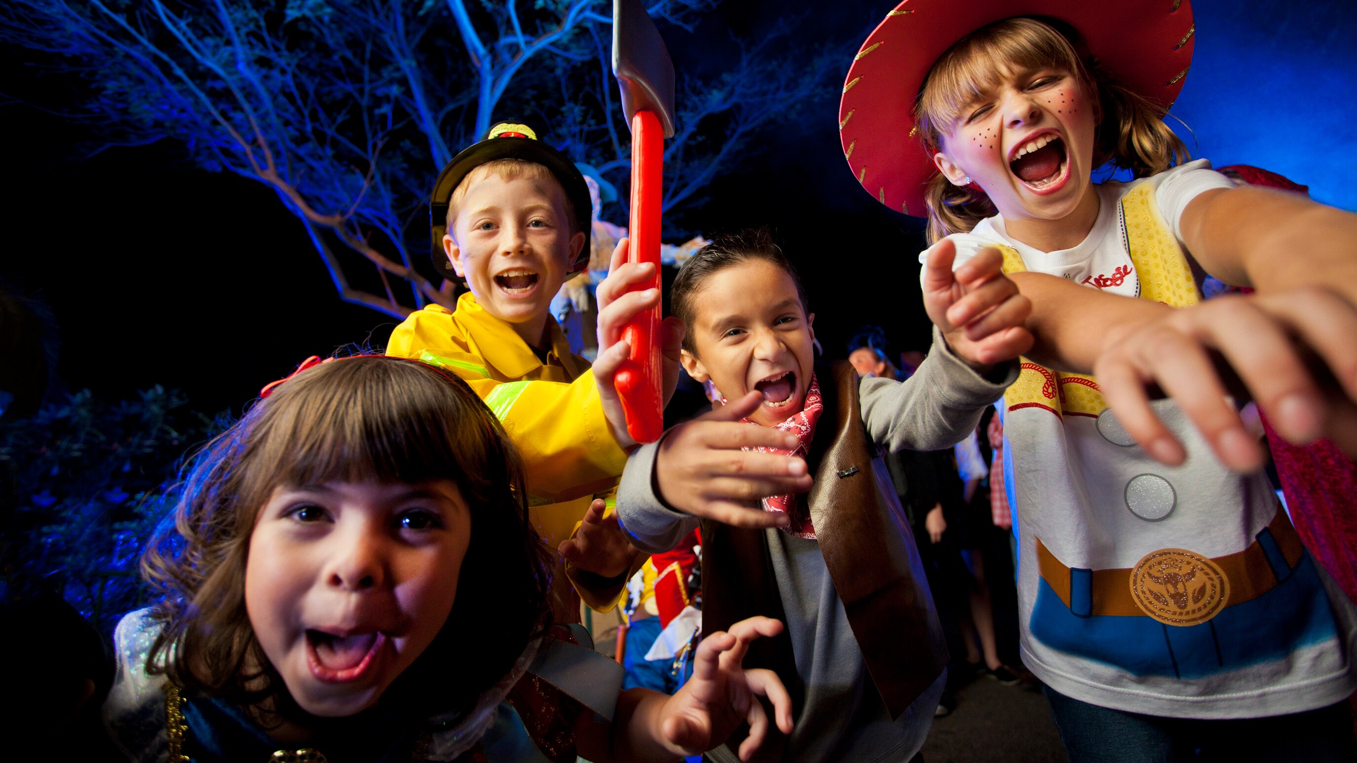 Four happy children dressed in Halloween costumes while outside at night