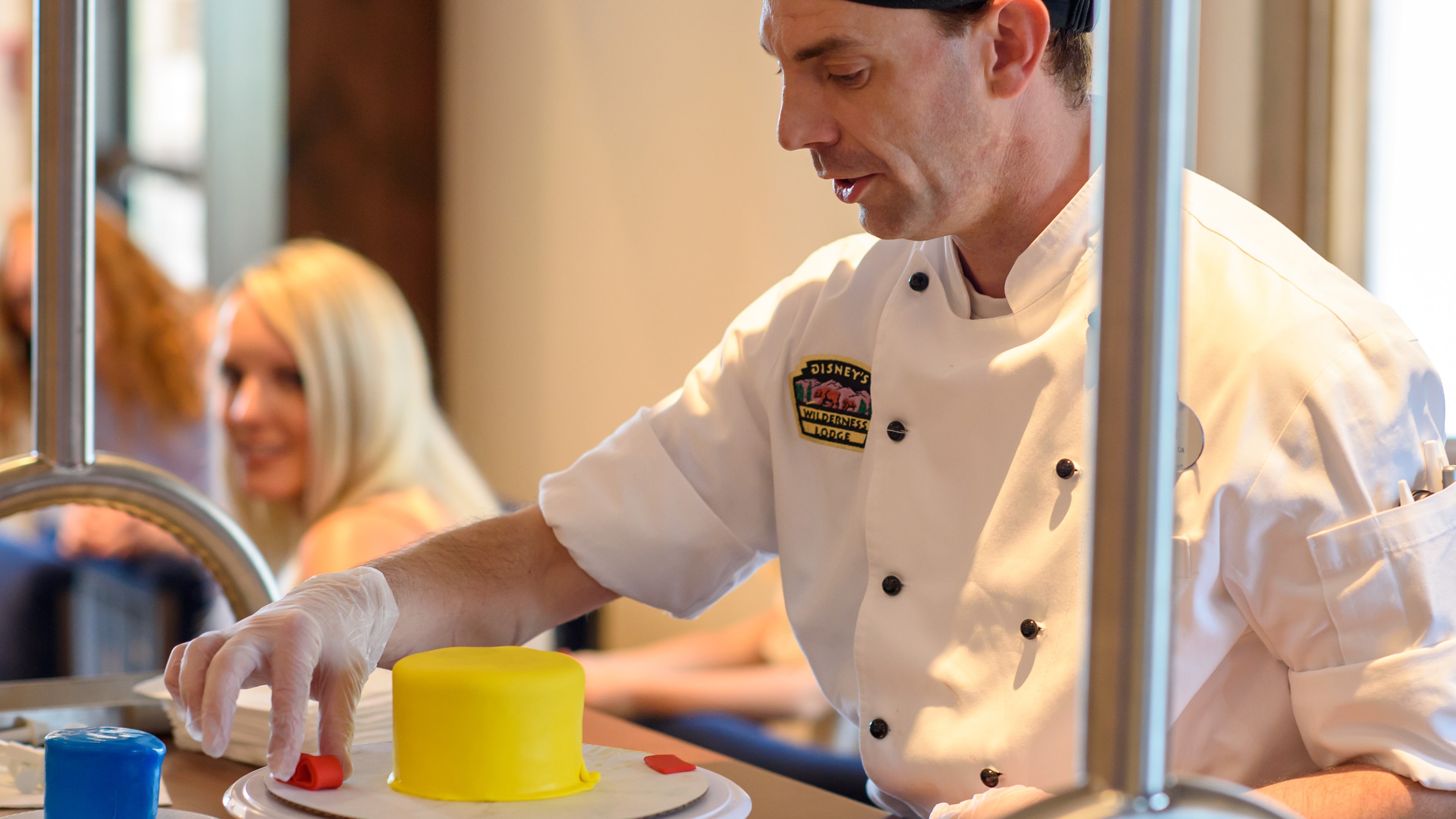 A pastry chef molds fondant into a bow to decorate a cake during a class at Reunion Station
