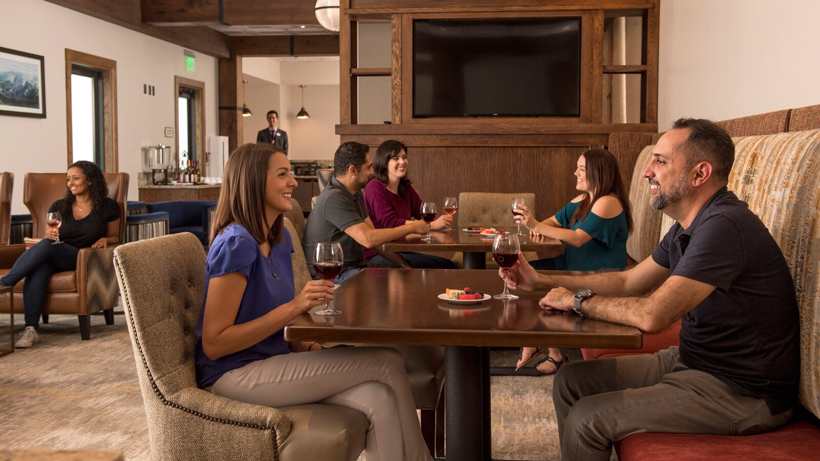 A couple enjoys glasses of wine and a small snack while seated at a table in the Reunion Station lounge