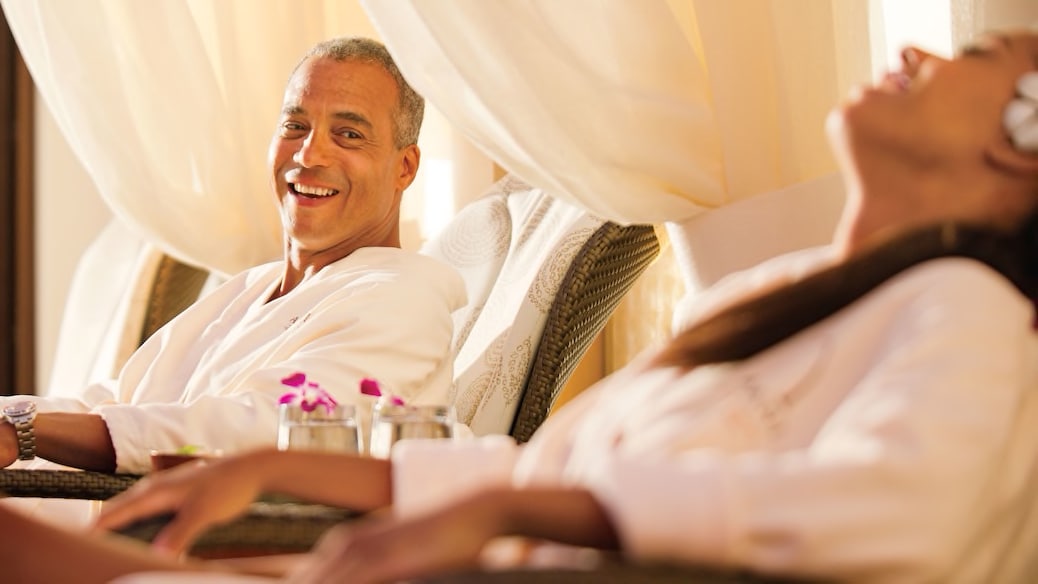 A man and a woman in plush robes relax in cushioned lounge chairs