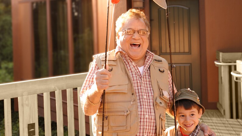 A man and his grandson dressed in fishing gear and carrying fishing poles