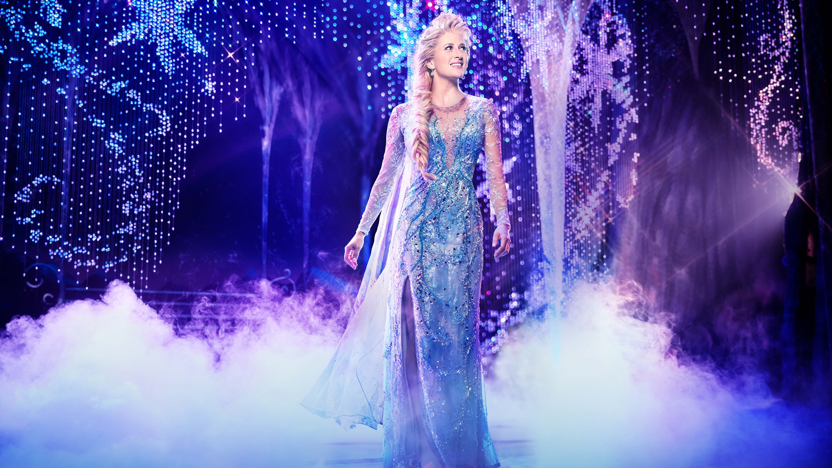 An actress portraying Elsa wears a long evening gown on fog filled stage during a scene in Frozen