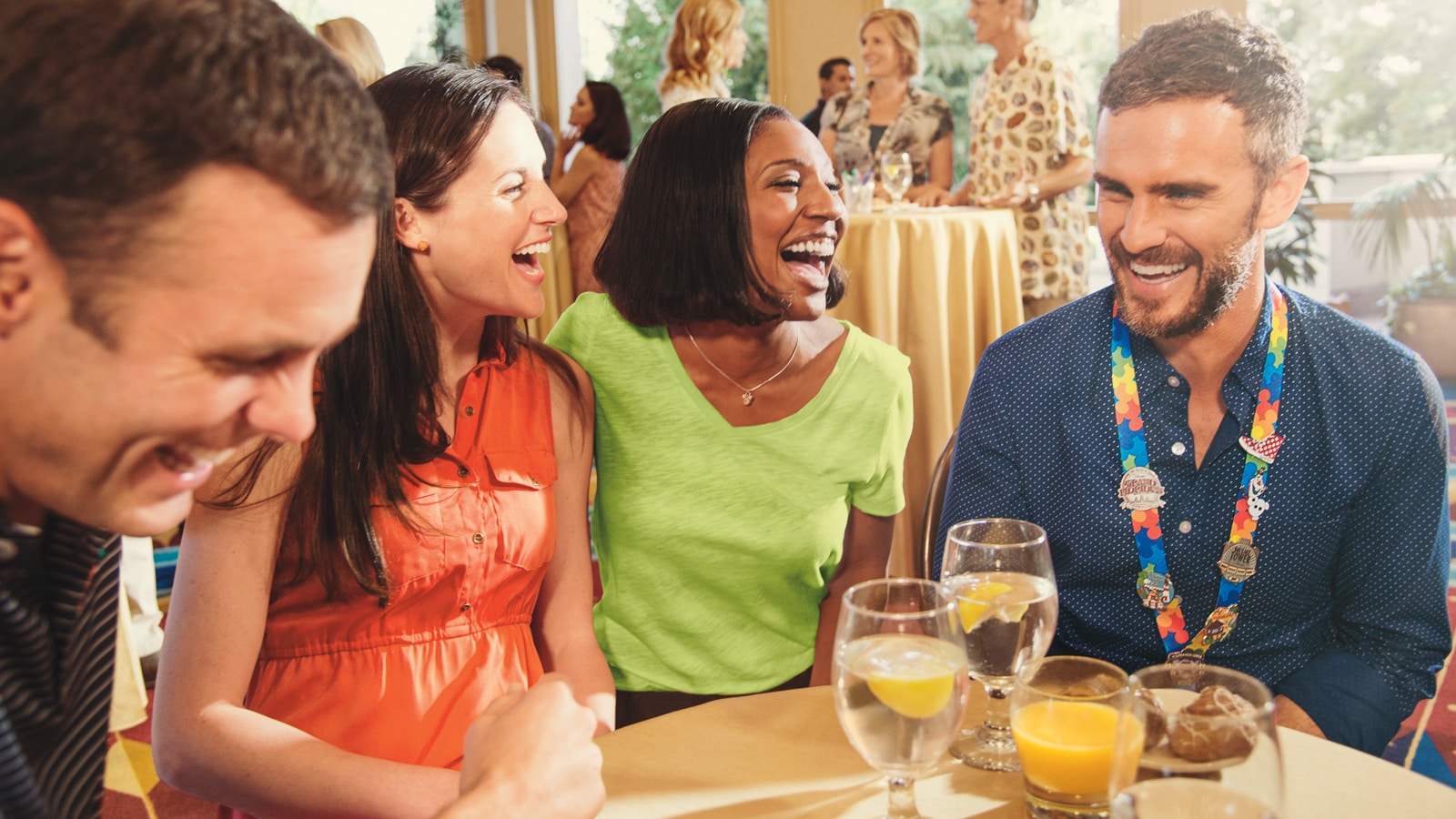 2 men and 2 women laugh as they gather around a table with 4 beverages