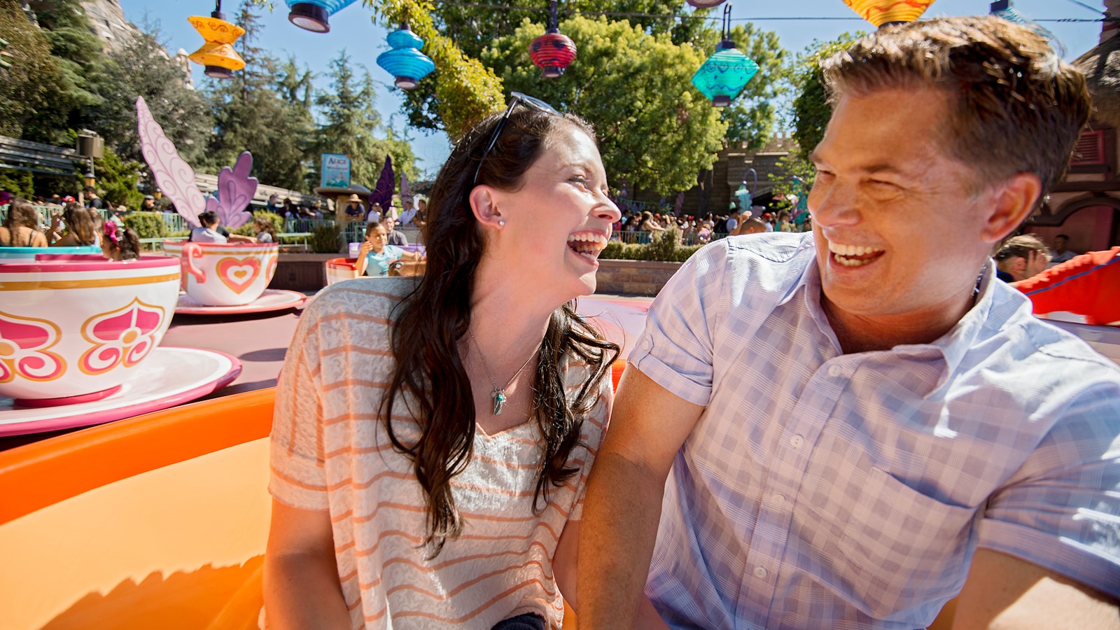 A man and a woman smile as they spin around in tea cups at the Mad Tea Party attraction