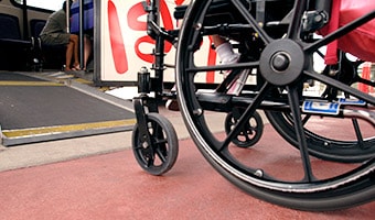 A wheelchair in front of a small ramp leading onto a Disney Transport bus