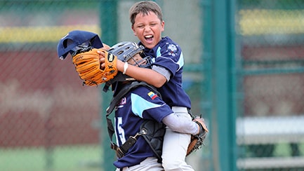 A baseball catcher hugging his teammate