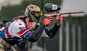 A paintball player aiming a paintball gun