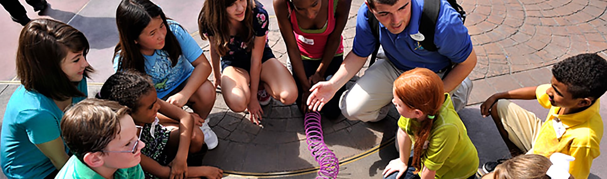 Children holding a Slinky in a circle with a Cast Member 