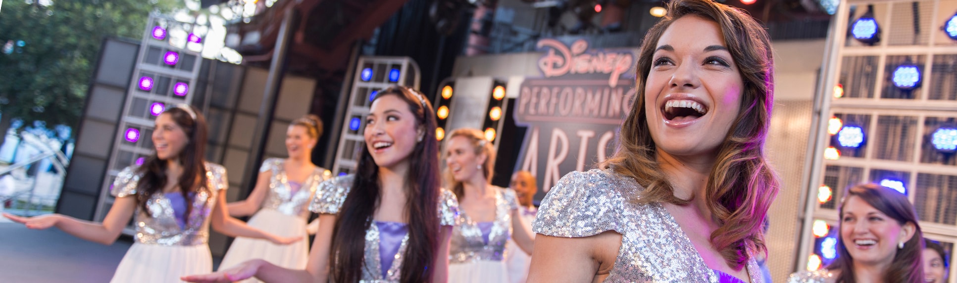Young performers wearing costumes smile and strike a pose