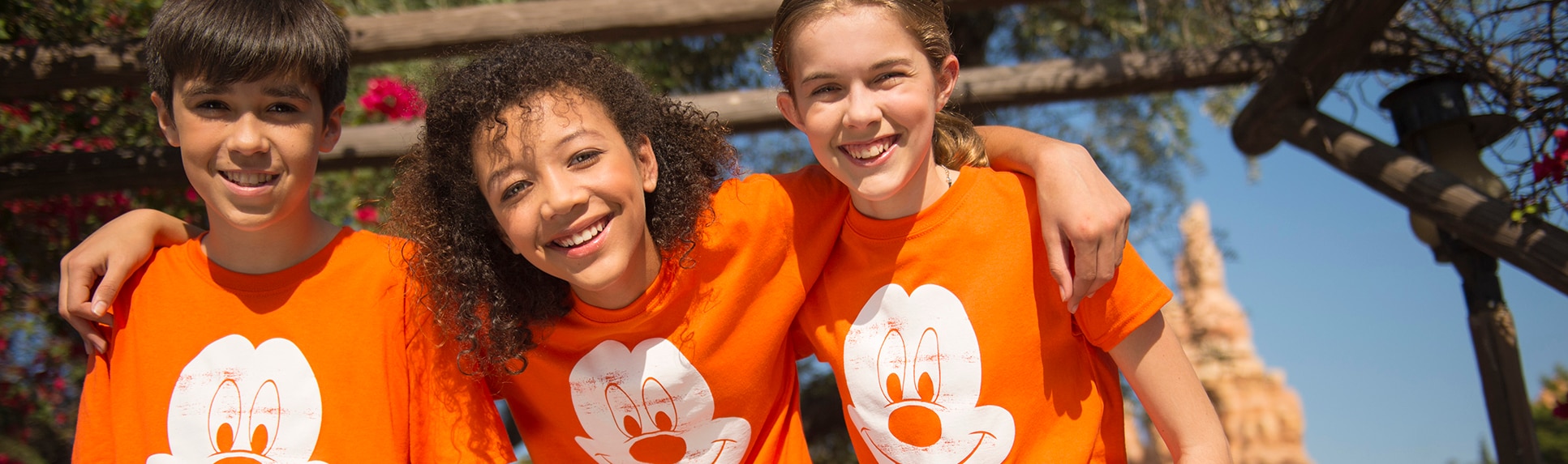 Smiling kids wearing matching shirts with Mickey Mouse logos