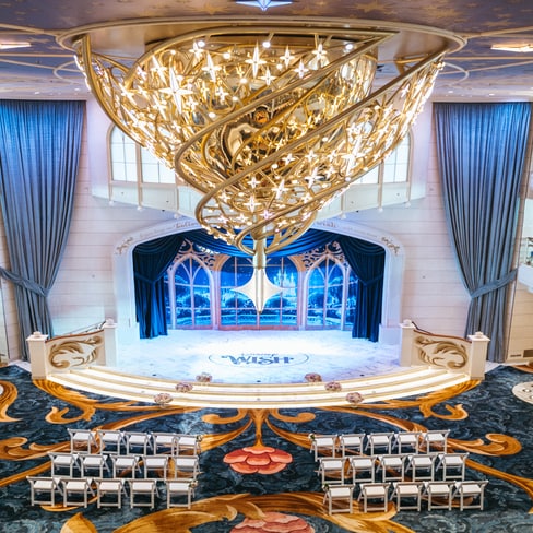 An ornate chandelier above the stage at the Grand Hall on the Disney Wish